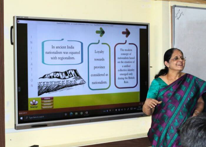 Teacher explaining historical concepts using advanced digital tools in the classroom at NewAge World School, Yelahanka.