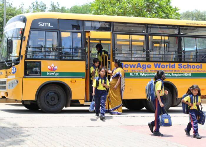 Students stepping off the NewAge World School bus, highlighting secure in-house transportation services for Yelahanka students.