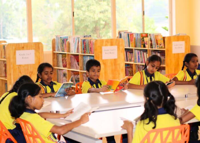 Students exploring books in the well-equipped library at NewAge World School, Best International School in North Bangalore.