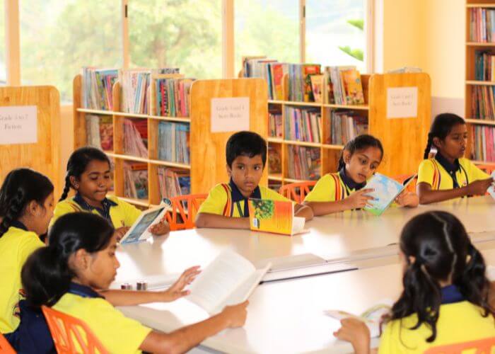Students enjoying reading activities in the spacious library at NewAge World School, fostering educational excellence in Yelahanka.