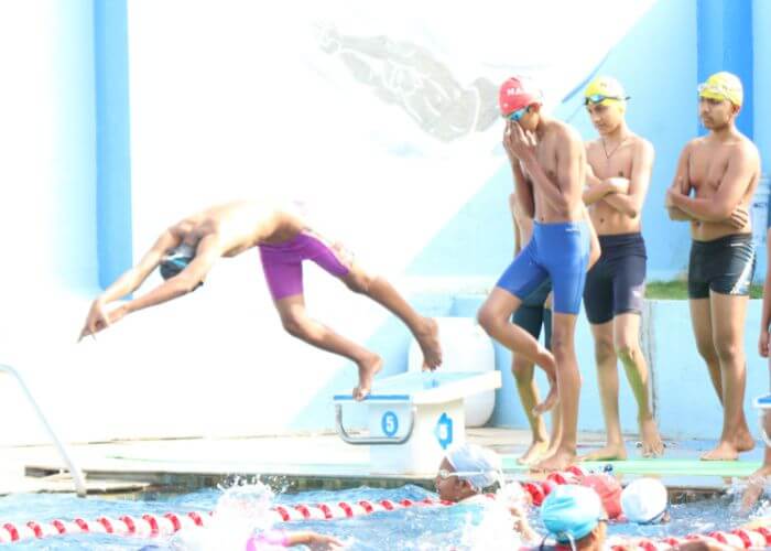 Swimming lessons in progress with students diving into the pool at the school’s sports facility in Bangalore.