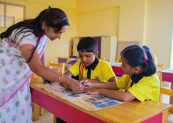 Teacher guiding students in a personalized learning session under the child-centric and focus group program at NewAge World School.